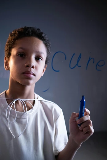 a boy writing on a wall while holding a blue cell phone