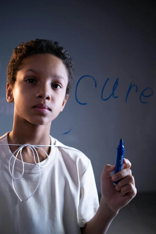 a boy writing on a wall while holding a blue cell phone