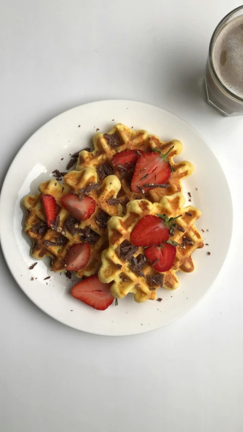 the waffles are arranged on a plate, on a table with a glass of milk