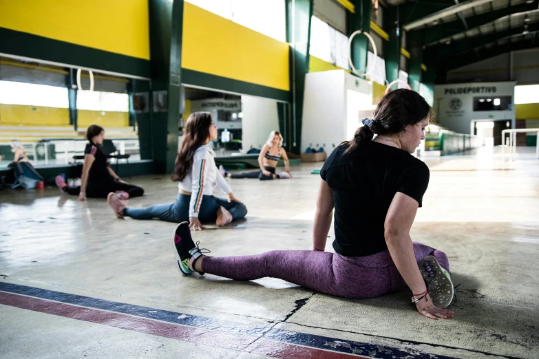 several young women sit in an indoor gym