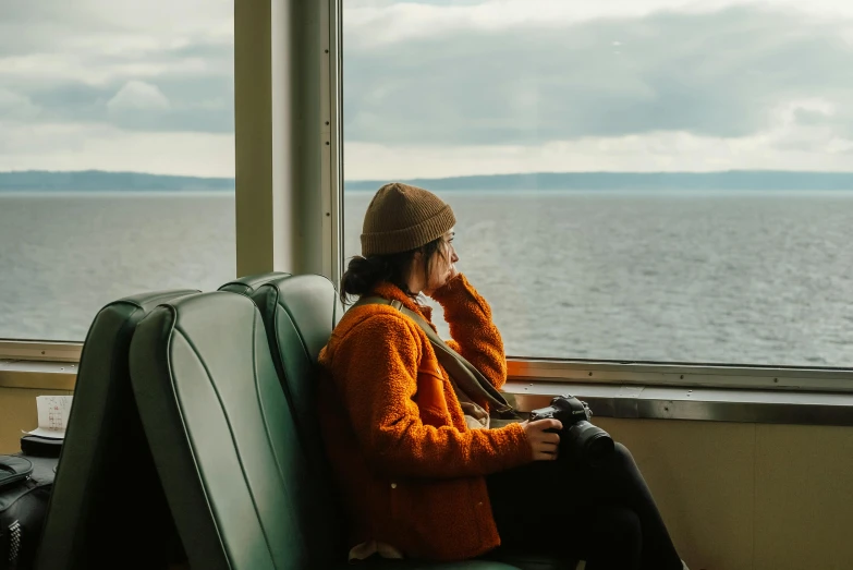 a person sitting on a seat looking out the window at the ocean