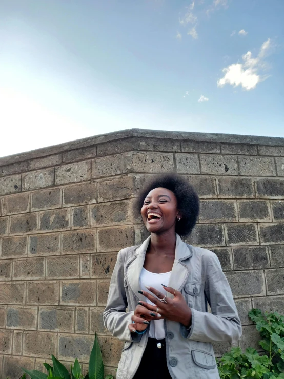 a woman stands by a wall and smiles