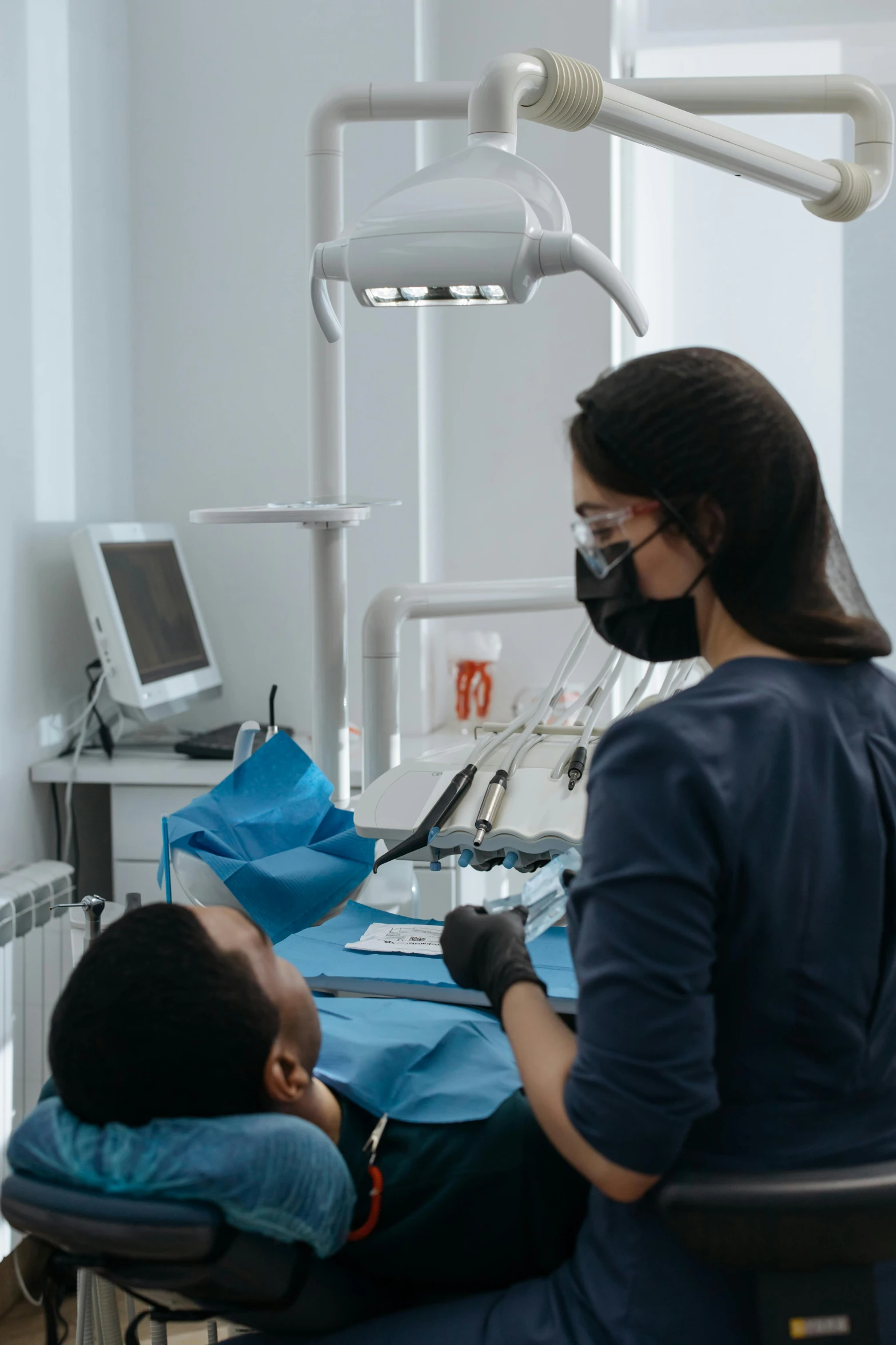 a dental technician examining a patient's teeth with two surgical equipment