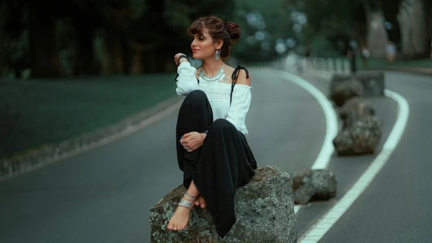 a woman sitting on rocks in the middle of a road