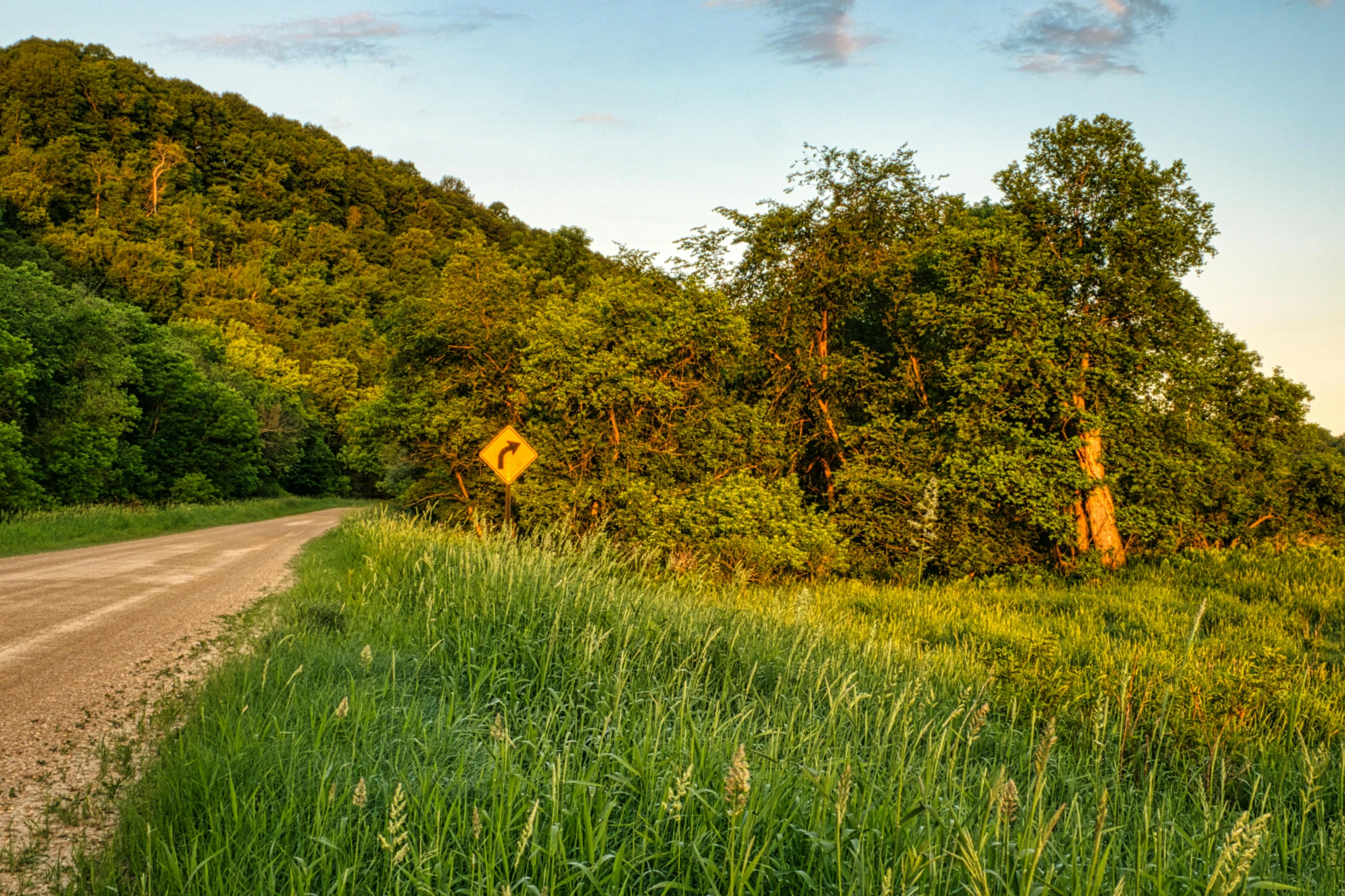 the road is lined with green, tree covered hills