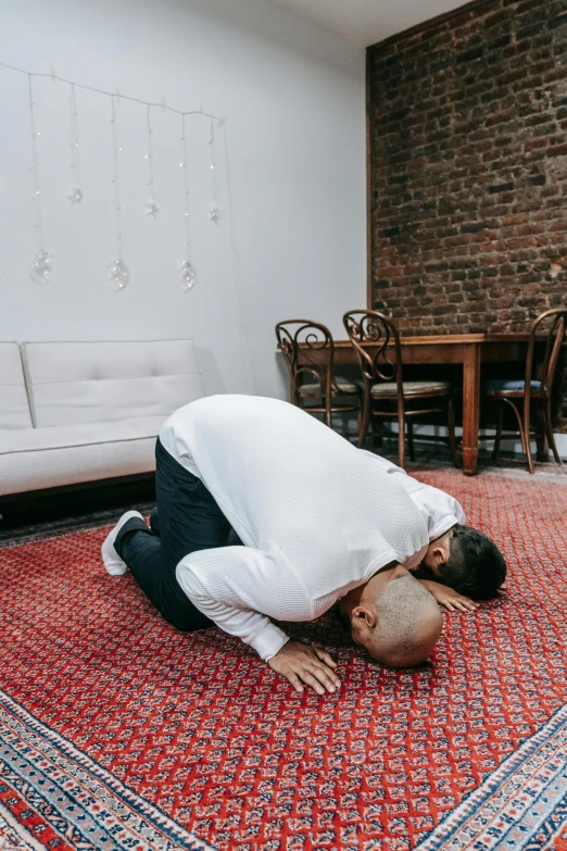 a man kneeling on top of an orange rug