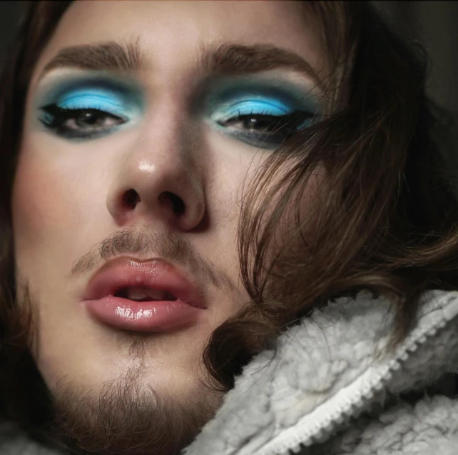 a man with bright blue and green eye shadow makeup