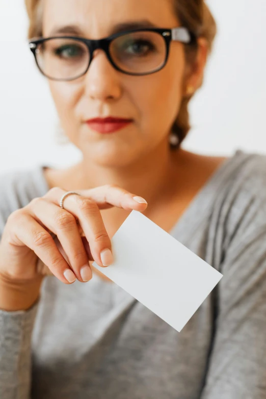 a woman wearing glasses holding a white business card