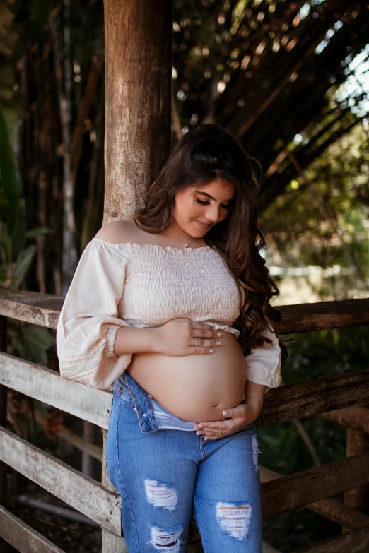 a pregnant woman is standing on a fence posing for her family pictures