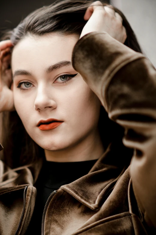 a woman putting on makeup while standing next to a brick wall