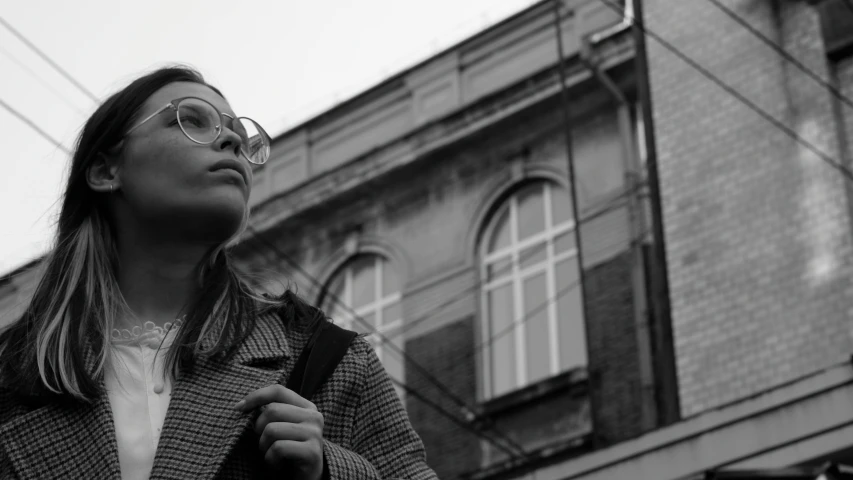 a woman standing next to a building in front of a bricked building