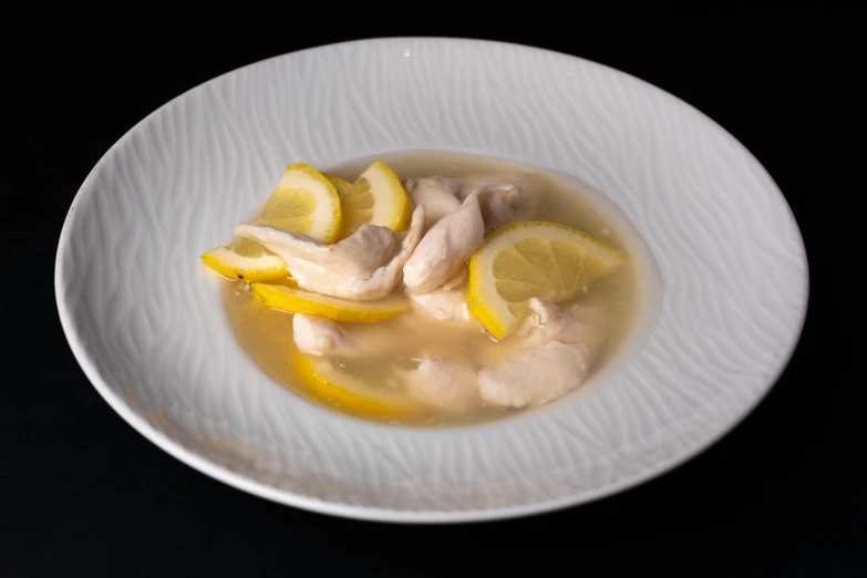 a bowl of soup with lemon wedges and chicken 