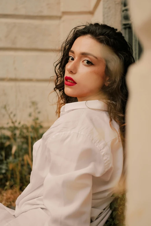 a girl is sitting outside wearing a white shirt