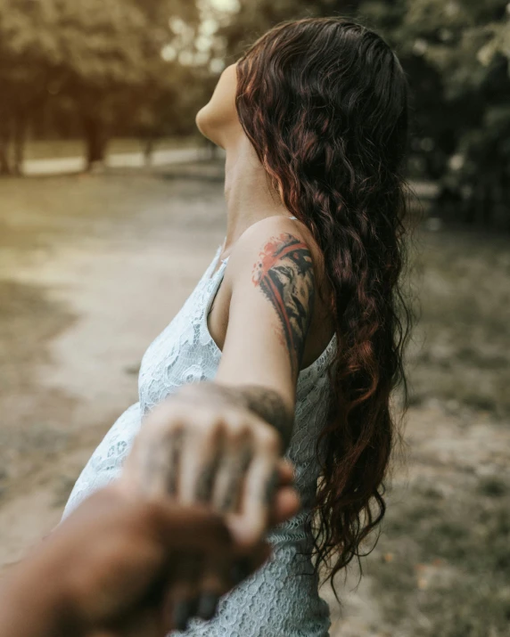 a woman with a tattoo on her arm holding a hand