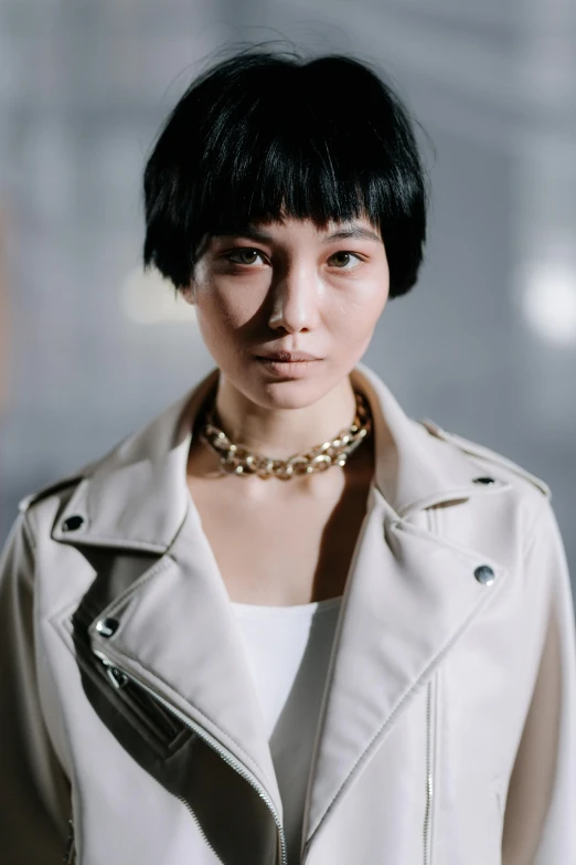 a woman wearing a leather jacket, white shirt, and gold chain necklace