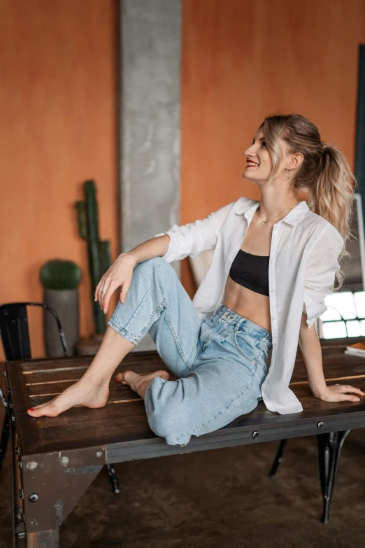 a woman wearing jeans and jacket sitting on a wooden bench