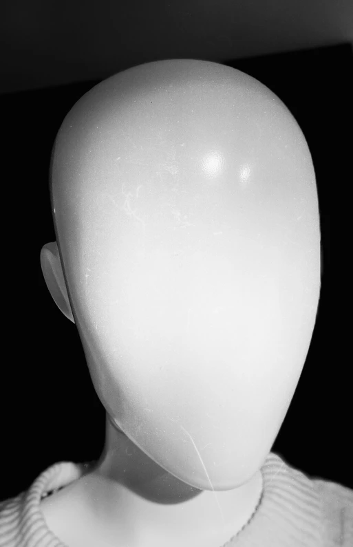 a white mannequin is standing on display in a black room