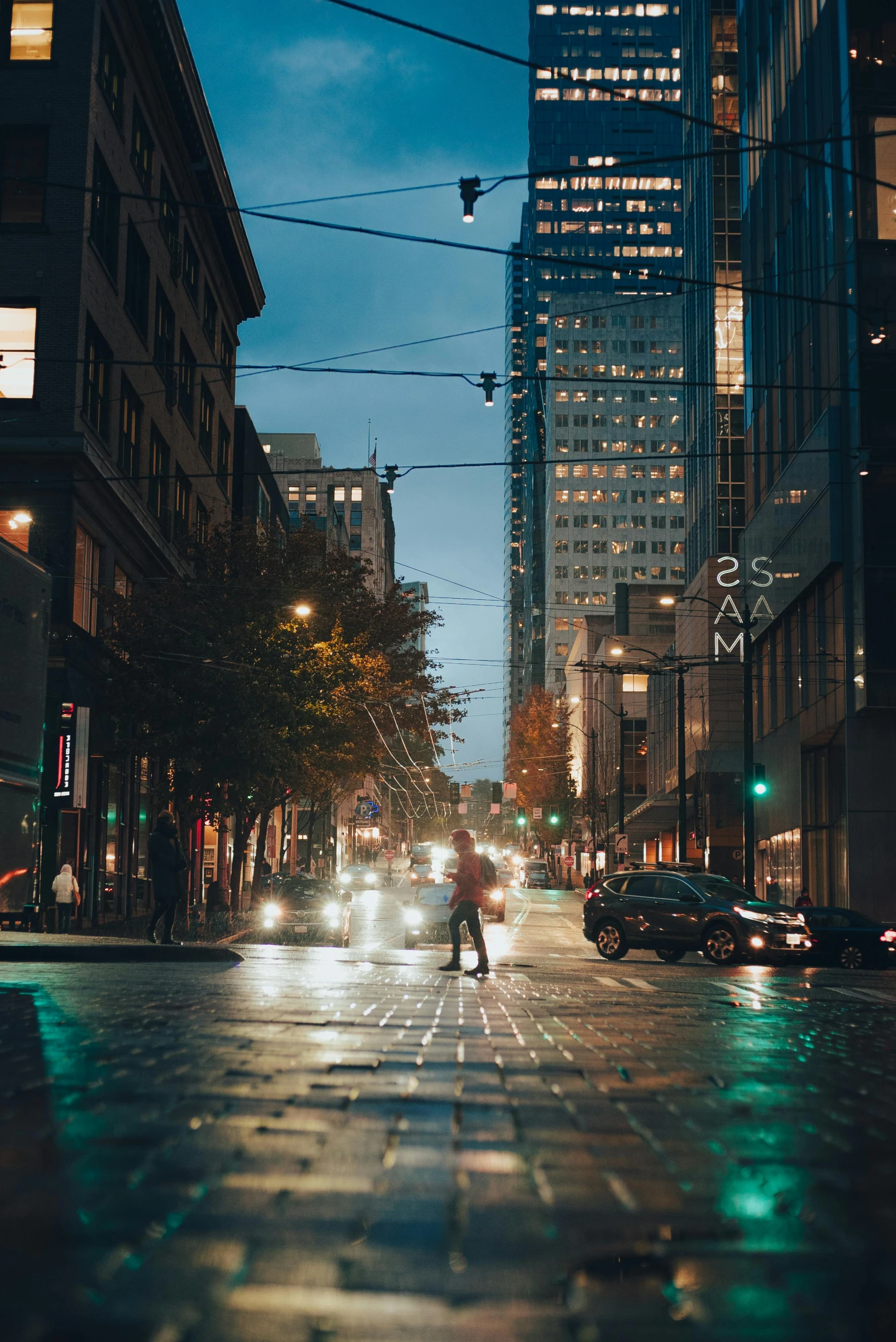 a rainy evening on a city street with cars and a man