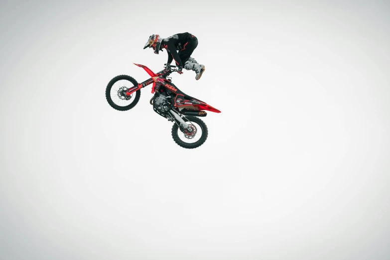 an extreme biker in black clothing performing an aerial trick