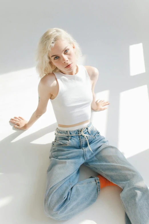 the young blonde girl poses in a white tank top