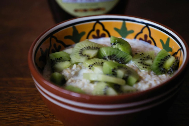 the bowl of oatmeal has kiwi slices and is ready to eat