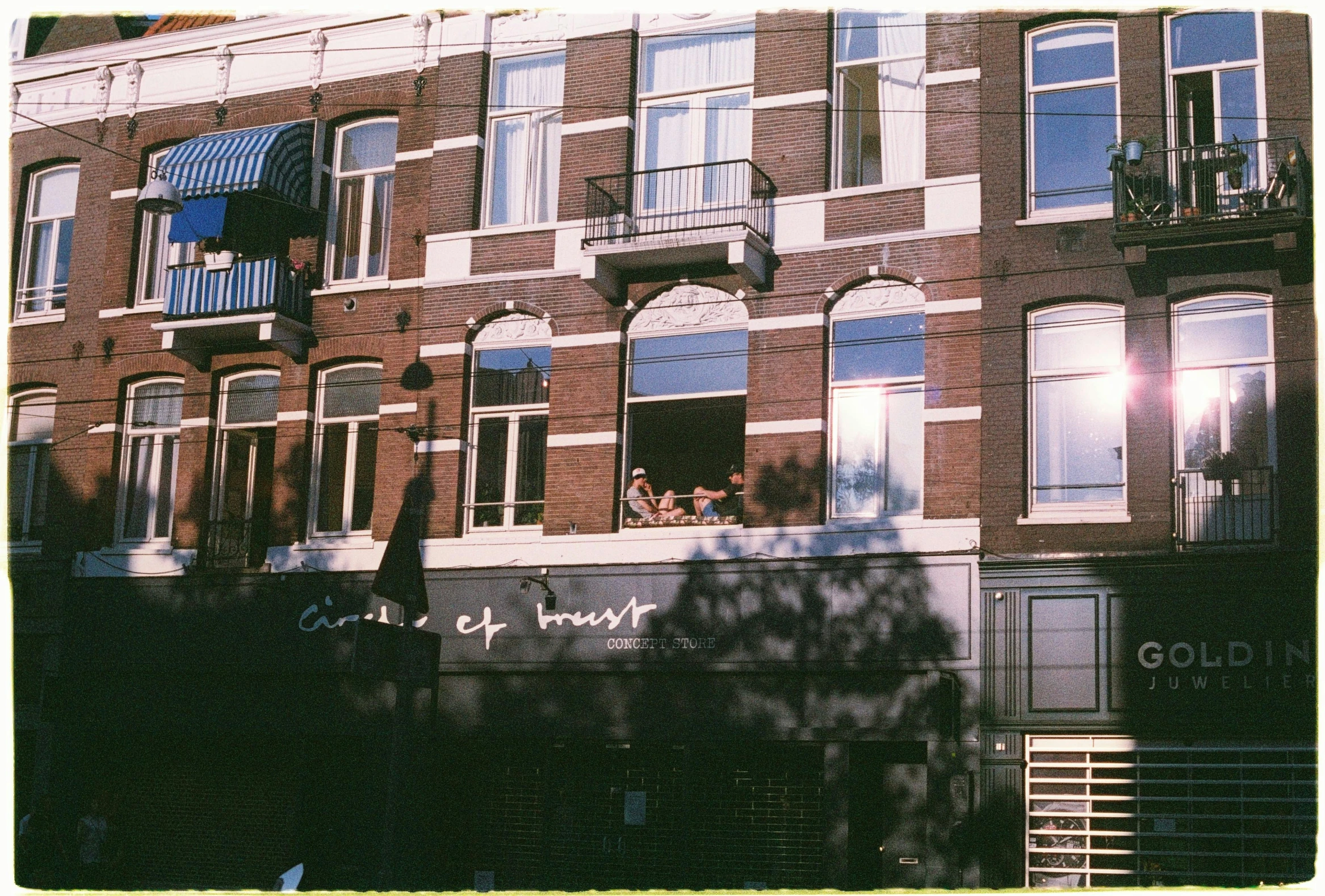 two people stand in the window looking out of a brick building