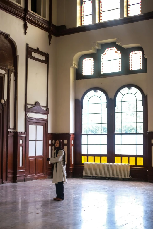 person with a coat and jacket, standing in front of large windows