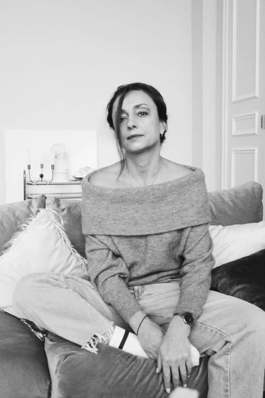 a woman in a sweater sitting on top of a couch