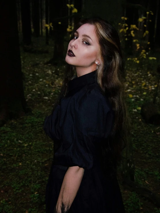 a woman in black in the dark near trees