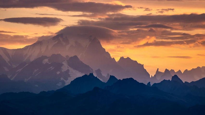 a mountain range as the sun rises with clouds