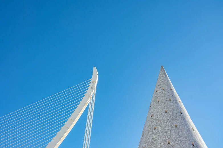 a couple of tall white structures next to a large bridge