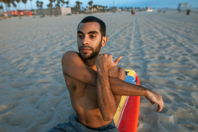 a man sitting on top of a surfboard at the beach