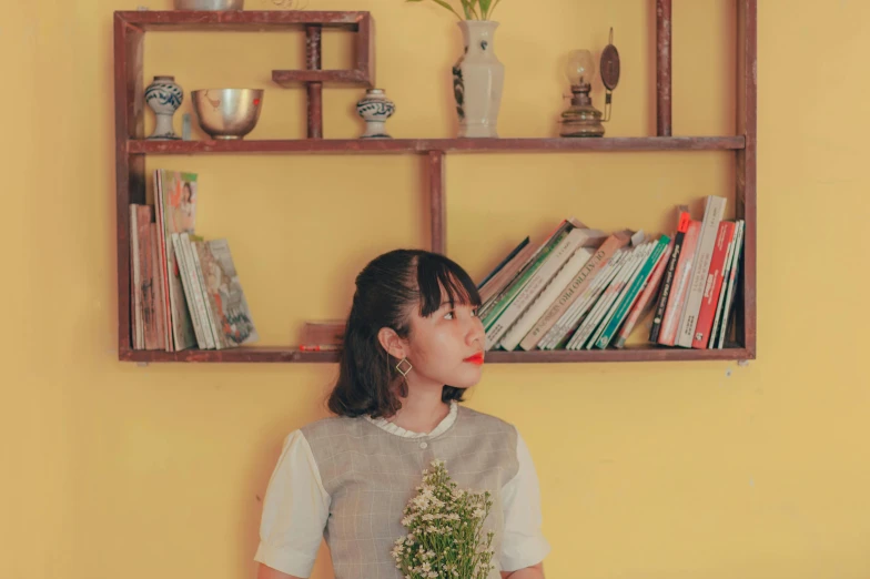 girl with flower in hand and a book shelf