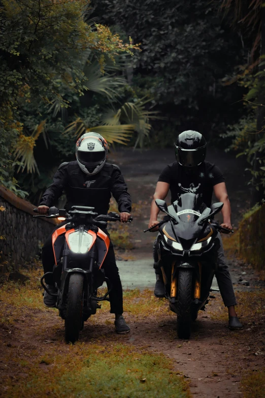 two men riding motorcycles down a dirt road