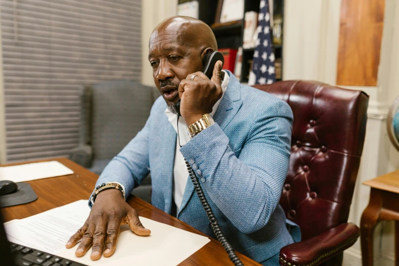 a man sitting at his desk talking on the phone