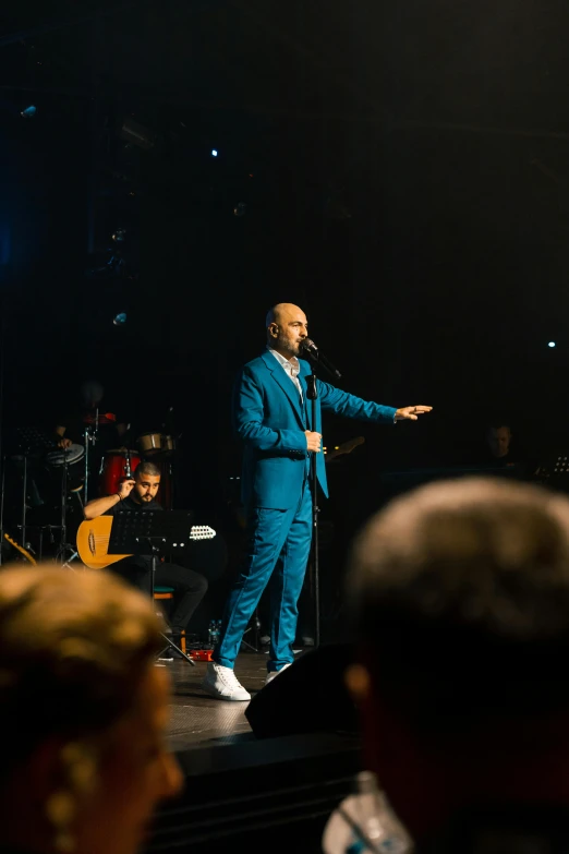 man in blue suit performing at a concert