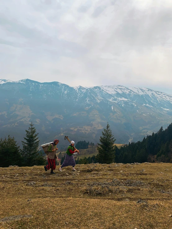 a man and woman carrying items on top of a mountain