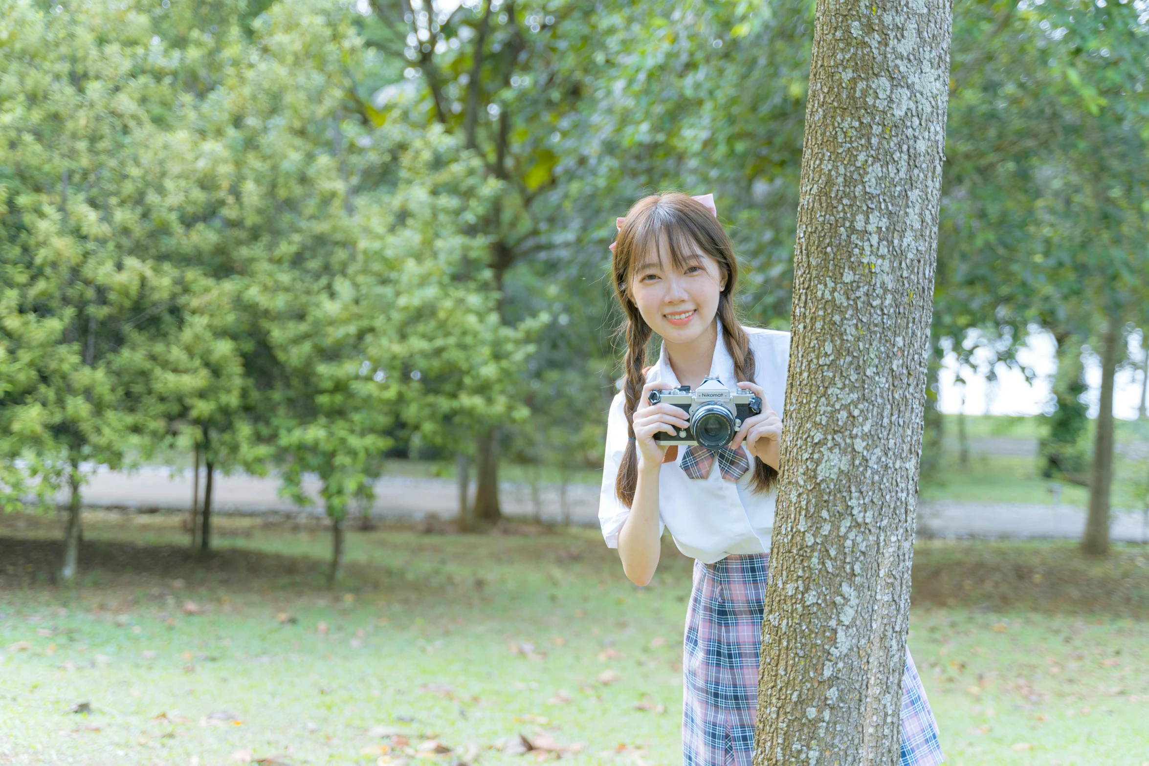 a woman holding a camera standing next to a tree