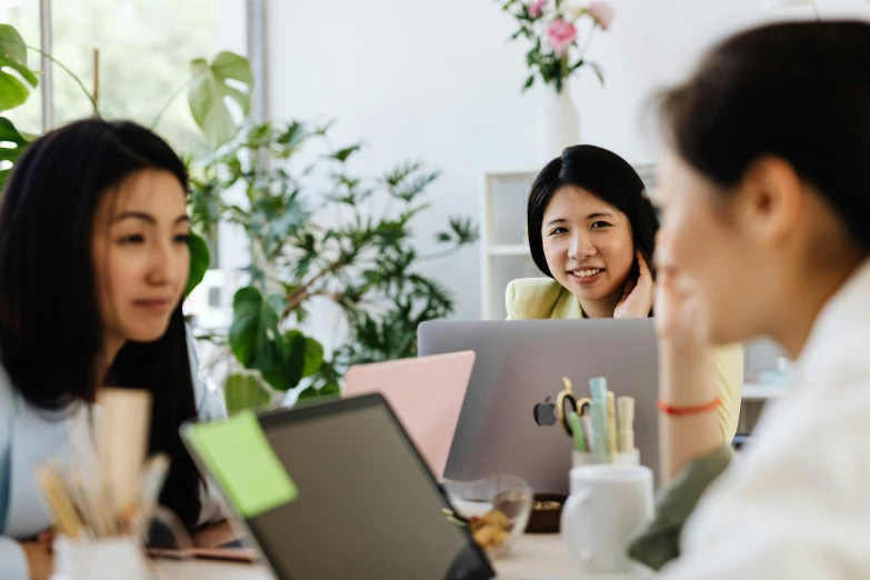 a group of women at a table with laptops