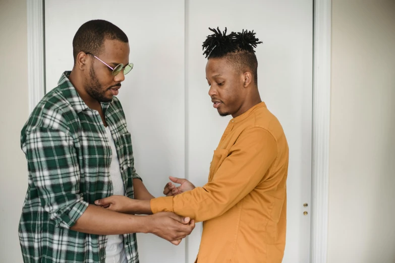 two men, one looking at the other hand while standing together