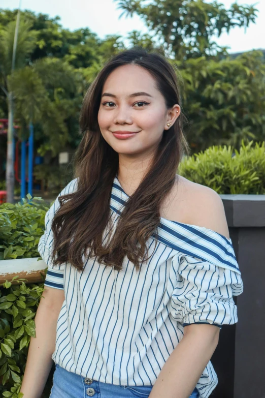 an asian girl posing in front of bushes