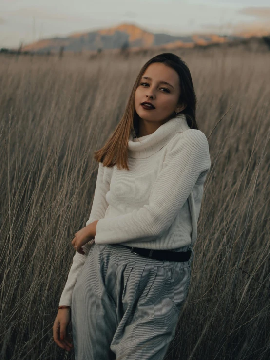 a girl poses in front of tall grass