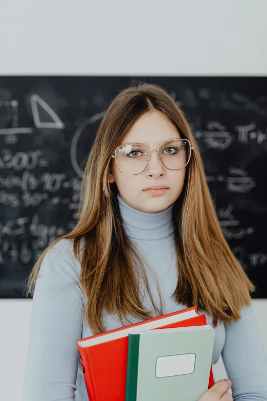 girl in blue sweater holding book and wearing glasses