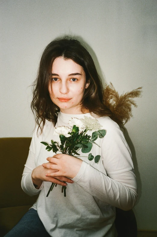 a woman in white sweatshirt holding flowers on couch