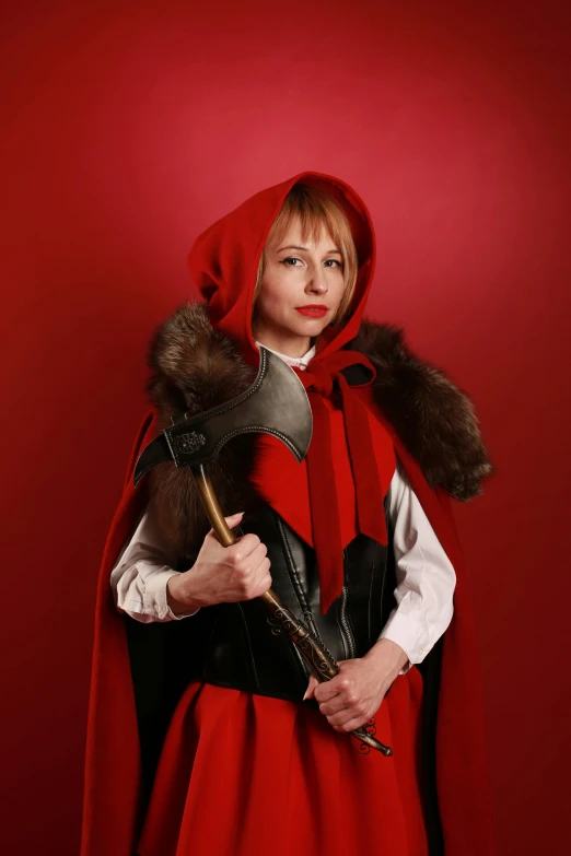 a woman in medieval red coat holding an axe