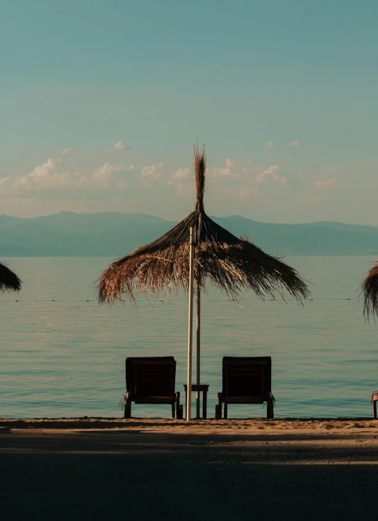 some chairs with umbrellas sitting by a beach