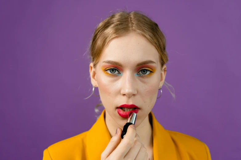 a woman with blue eyes has a red lip and bright make - up