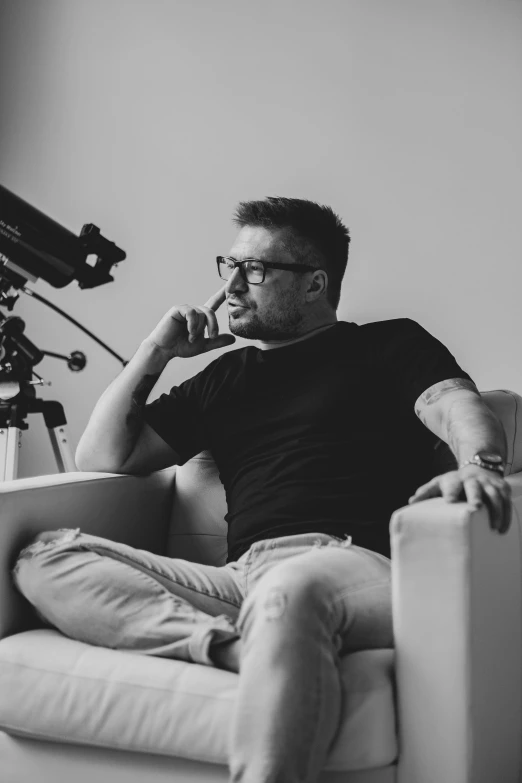 black and white po of man sitting in chair using phone