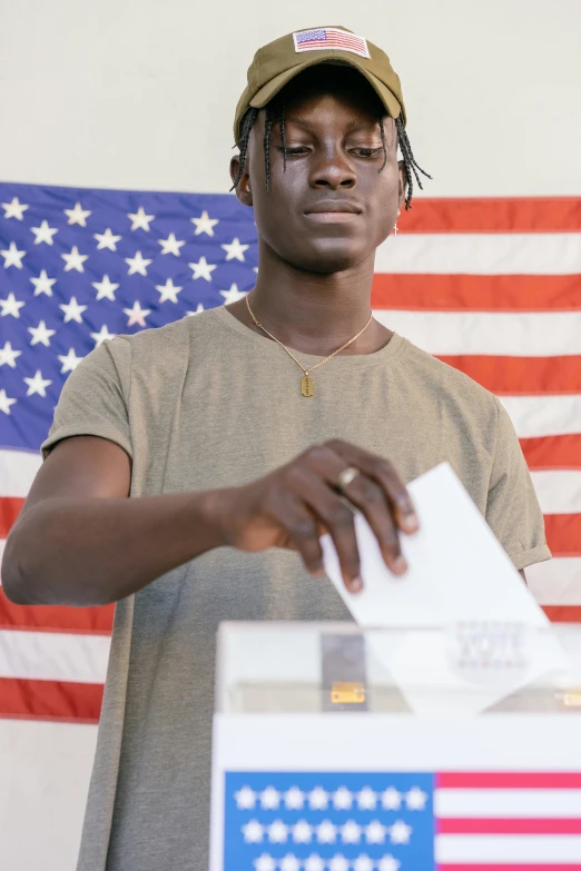 a man holds his voting papers next to an american flag