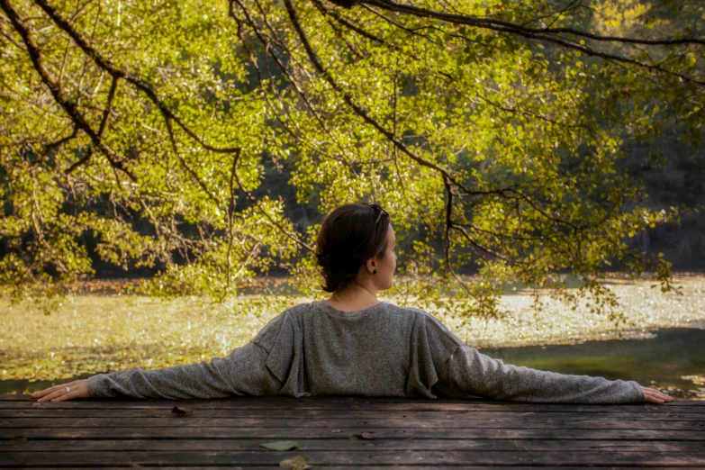 a woman sitting at a picnic table looking over the water